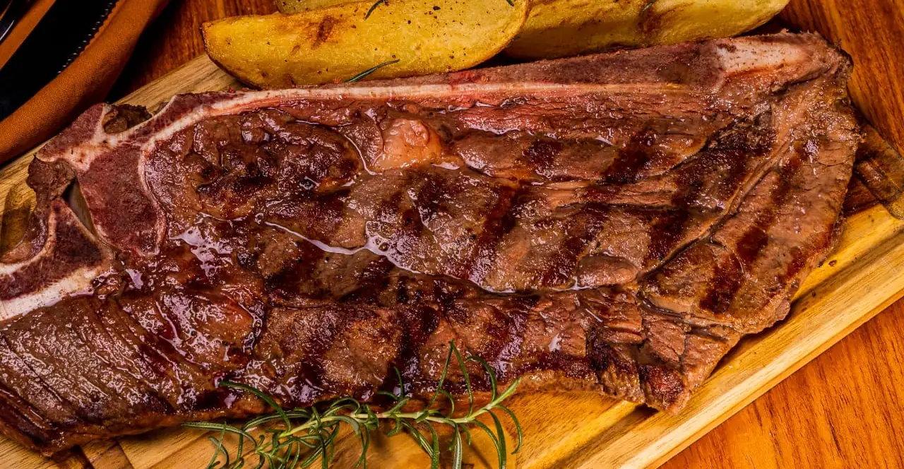 T-bone na brasa com marcas da grelha, batatas rústicas e alecrim, servido na tábua